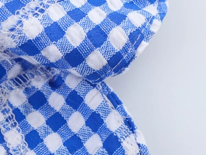 Close-up of blue and white plaid fabric with detailed white overlock stitching texture