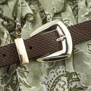 Ceinture marron gaufrée serpent avec boucle dorée sur une robe d'été à motifs