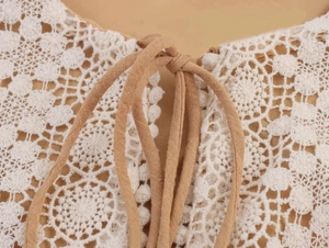 Dettaglio di pizzo bianco all'uncinetto su tessuto kaki con coulisse sullo scollo