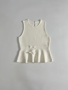 Détail du haut en tricot sans manches crème avec nœuds décoratifs et ourlet basque