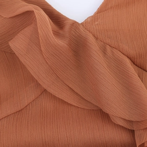 Gros plan sur le tissu plissé caramel et les détails de volants de la robe d'été