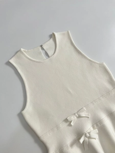 Détail du haut en tricot blanc sans manches avec nœuds délicats et texture de maille fine