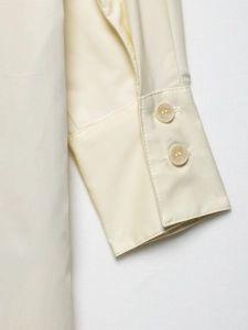 Detailansicht der Manschetten mit zwei Knöpfen an einem cremefarbenen Hemdkleid aus Baumwolle