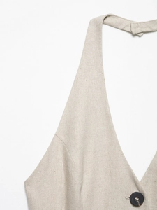 Detail of oatmeal linen vest featuring a deep V-neck, neck tie and dark button