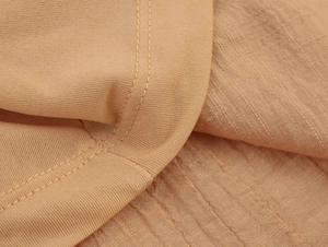 Dettaglio dell'abito estivo kaki che mostra il bordo in maglia e la trama del tessuto seersucker