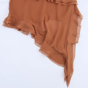 Détail de volants en mousseline caramel avec texture verticale sur une robe asymétrique