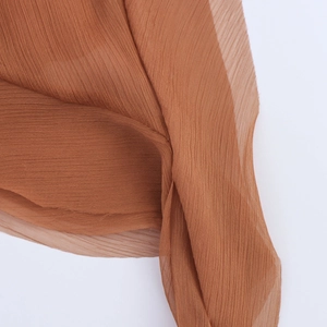 Détail de tissu plissé caramel avec texture translucide et fines plis verticaux