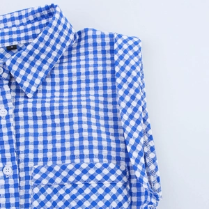 Blue and white gingham seersucker sleeveless romper with waist tie and buttons