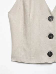 Detail view of cotton linen vest with V-neckline and textured dark brown buttons