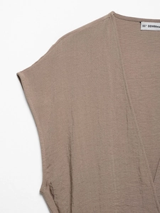 Dettaglio del gilet in lino con scollo a V che mostra la trama del tessuto e le cuciture
