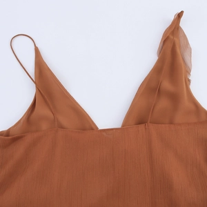 Détail de la bretelle asymétrique à volants et col en V sur une robe plissée caramel