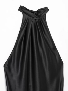 Détail d'un haut élégant en satin noir avec encolure croisée et plis sophistiqués