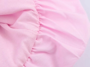 Detail von rosa Kleiderstoff mit feinen Raffungen und Rüschendetails bei sanftem Licht