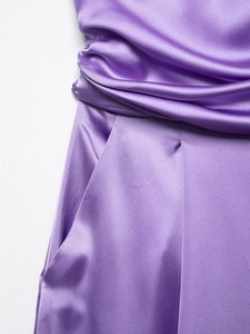 Detail of purple satin jumpsuit featuring elegant pleated waistline and invisible side pockets