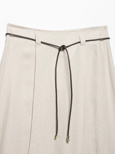 Close-up of beige linen fabric texture with a dark brown drawstring and gold metal tips