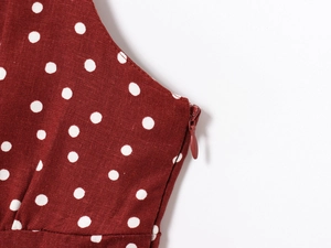 Detail of burgundy polka dot dress featuring a hidden zipper and fabric texture