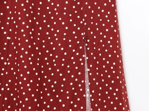 Detail of burgundy polka dot dress featuring a side slit and reinforced hem stitching