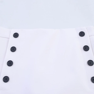 Detail of white high-waisted shorts with vertical rows of decorative black buttons