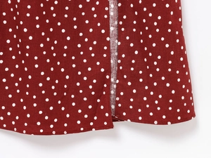 Detailed close-up of red polka dot dress hem with clean side slit stitching