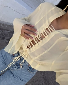 Detailed view of light yellow chiffon blouse featuring multi-layer lace-up ties and V-neckline