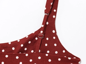 Detailed close-up of adjustable straps and silver buckle on red polka dot summer dress
