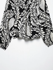 Detail of black and white tropical leaf print on women's blouse with elasticated cuffs