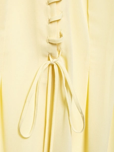 Detailed view of light yellow chiffon fabric featuring elegant criss-cross lace-up design