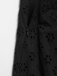 Detailed close-up of hollow embroidery fabric with invisible zipper on black dress