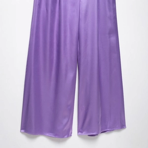 Elegant purple satin wide-leg halter jumpsuit with smooth silky texture and relaxed fit