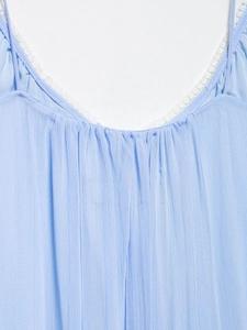 Detail of light blue pleated dress with lace trim and delicate spaghetti straps