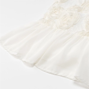 Détail de la broderie florale blanche en dentelle et volants en mousseline