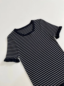 Détail du haut en maille à rayures noires et blanches avec poignets à volants et texture côtelée
