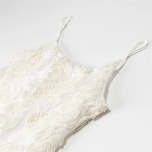 Détail de fleurs de rose 3D en tulle sur une robe d'été blanche à fines bretelles