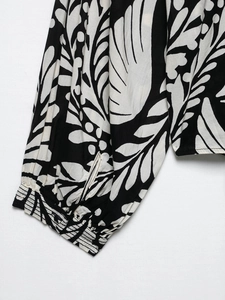 Close-up of black and white leaf print blouse showing ruched cuffs and stitching detail