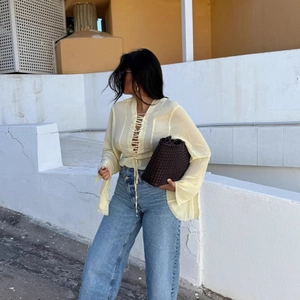 Pale yellow long sleeve tie-front blouse paired with light blue wide-leg denim jeans