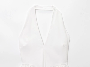 Detail of white halter neck top featuring deep V-neckline and elegant pleated waist texture