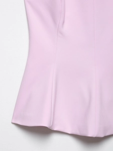 Detail of light pink sleeveless top showing smooth fabric texture and wavy hem stitching