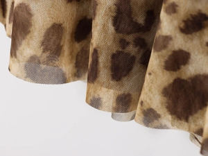 Detail of leopard print mesh fabric showing lightweight texture and pleated hemline