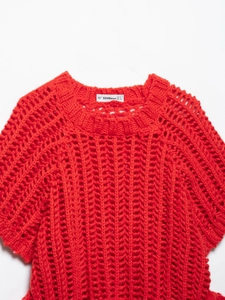 Détail du haut en maille crochet orange montrant l'étiquette et la texture