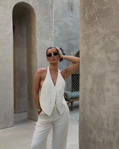 Detailed view of the white V-neck halter vest with tonal buttons and tailored fit