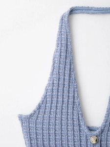Détail du tricot gaufré bleu et du bouton argenté gaufré sur l'encolure licou