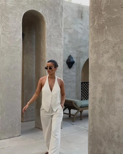 Detail of elegant beige V-neck halter vest and wide-leg trousers in street style setting
