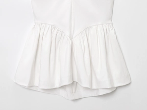 Macro detail of white halter top showing V-shaped waist seam and ruffled balloon hem