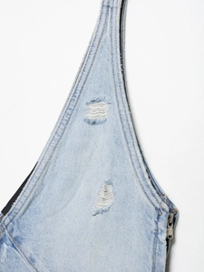 Detailansicht von hellem Denim-Stoff mit Destroyed-Effekten, Fransen und gelben Kontrastnähten