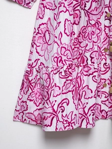 Close-up of pink floral seersucker fabric with wooden buttons and ruffled edge detail