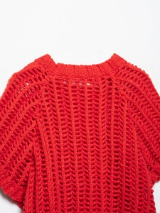 Gros plan sur un haut en maille rouge vif avec motif ajouré en crochet style arête de poisson