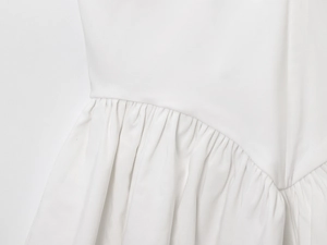 Macro detail of the pleated fabric texture and stitched seams on a white halter top