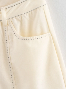 Détail des coutures contrastées sur la taille et la poche du short en jean crème