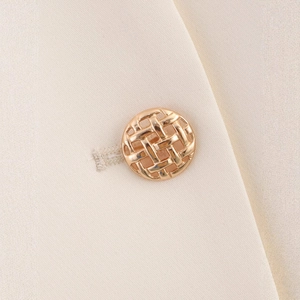 Close-up of golden textured button on a beige halter neck vest for women
