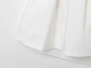 Detail of white balloon top showing soft pleated fabric and wavy hemline texture